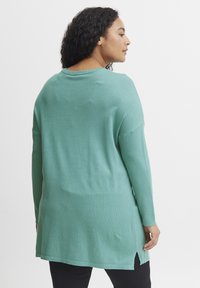 Maglione verde menta a maniche lunghe con vestibilità ampia, spacchi laterali all'orlo e scollatura ampia. Realizzato in morbido tessuto a maglia testurizzato.