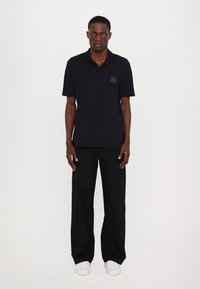 Must have logo patchiga must shirt, mugavad mustad püksid ja valged sneaksid.