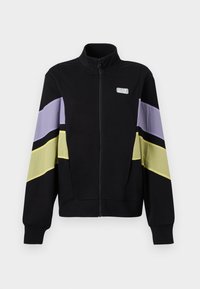 Veste noire à fermeture éclair avec col montant, présentant des rayures diagonales lavande et jaune pâle sur les manches et le logo EA7 sur la poitrine.