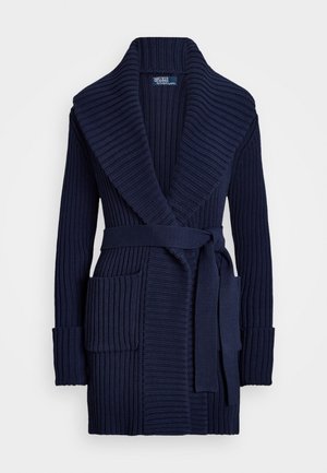 Marineblauer gerippter Strickcardigan mit einem Schalkragen, zwei vorderen Taschen, einem Bindegürtel und langen Ärmeln. Strukturierter Stoff verleiht Tiefe.