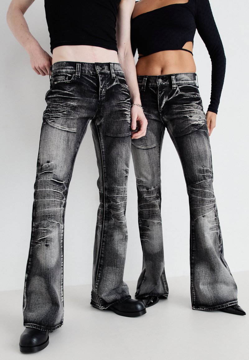 Uppblåsta svarta jeans i denim med en urblekt, sliten textur och revor, med en klassisk fem-ficksdesign och kontrasterande sömmar.