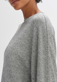 Maglione grigio con texture a coste, scollatura arrotondata e vestibilità morbida. Presenta un delicato motivo a spina di pesce e maniche abbassate.