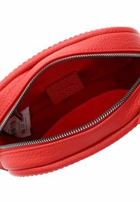 Rode leren tas met een gestructureerd oppervlak, voorzien van een zilveren rits, een binnenvak en een slank rond model. Binnenin gevoerd met rode stof.