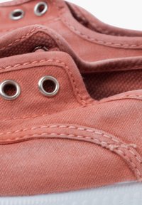Scarpe in tela color corallo con suole in gomma bianca, dotate di occhielli in metallo e dettagli cuciti. Il tessuto ha una finitura liscia e strutturata.