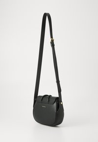 Borsa a tracolla in pelle nera con forma curvilinea, dotata di chiusura a patta, dettagli in metallo dorato e tracolla regolabile.