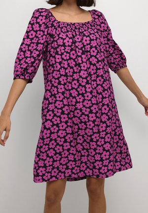 Sukienka z krótkim rękawem i kwadratowym dekoltem, wykonana z czarnej tkaniny pokrytej dużymi, jaskrawymi różowymi kwiatowymi wzorami. Lekka i zwiewna konstrukcja.