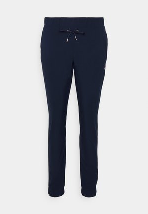 Tamsiai mėlyni sportiniai kelnes, pagamintos iš minkštos medžiagos, su elastinga juosmens juosta ir šnypščioju užtrauktuku keliuose, leidžiančiu pritaikyti dydį.