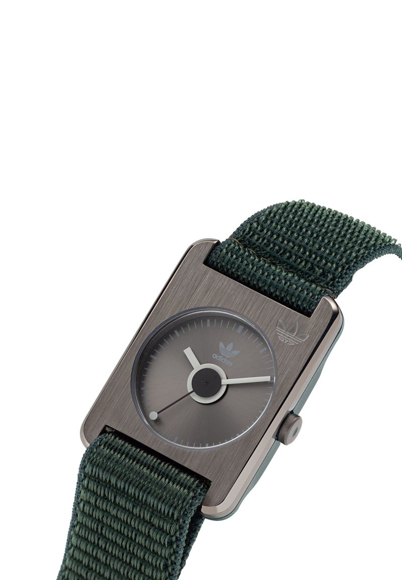 Montre-bracelet rectangulaire Adidas avec boîtier en métal brossé, cadran rond sombre, aiguilles blanches des heures et minutes, et bracelet en tissu tissé vert.