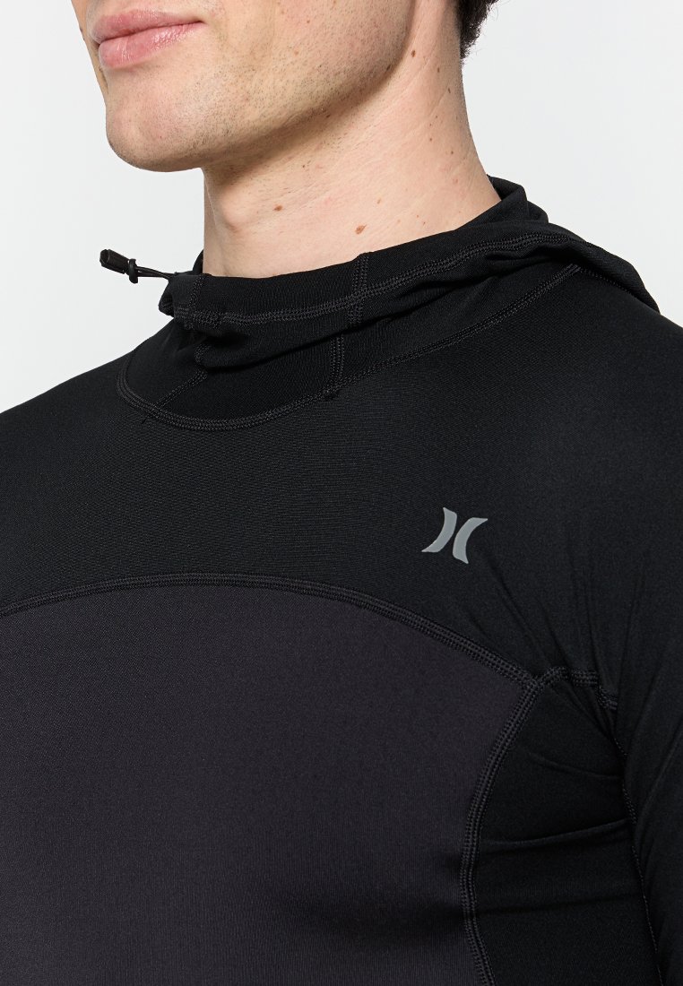 Czarna koszula z długim rękawem z wysokim kołnierzem i regulowanymi sznurkami. Posiada gładką teksturę i małe szare logo na piersi.