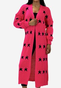 Long gilet rose en matière tricotée, avec des accents d'étoiles noires disposées en motif répétitif, à coupe décontractée et à devant ouvert.