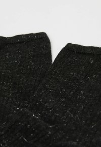 Černé pletené ponožky s žebrovanou strukturou, s mírně chlupatým povrchem a ohrnutými manžetami. Bez viditelných vzorů nebo kovových detailů.