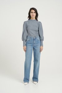 Gray long-sleeve blouse with puffed shoulders, styled with high-waisted light blue wide-leg jeans and white pointed-toe shoes.