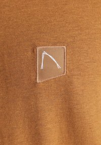 Burnt orange Stoff mit glatter Textur, der ein quadratisches Stück mit einem weißen, minimalistischen Design zeigt, das in der Mitte gestickt ist.