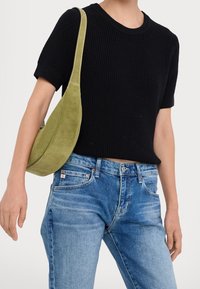 Haut court en maille côtelée noire à manches courtes, jean en denim bleu clair et sac à main en daim vert avec une forme incurvée et des coutures contrastantes.