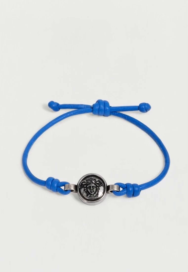 Bracelet en cordon bleu avec un nœud coulissant réglable et un médaillon rond argenté orné d’un visage sculpté.