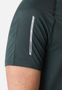 Groene sportshirt met geperforeerde stof, een slim fit ontwerp en een verticale reflecterende accent met "SWEDEMOUNT" op de mouw.
