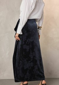 Langer, marineblauer Samtrock mit einem geprägten Blumenmuster, der sanft von der Taille fällt, mit einer Seitenpartie für zusätzliche Design-Details.