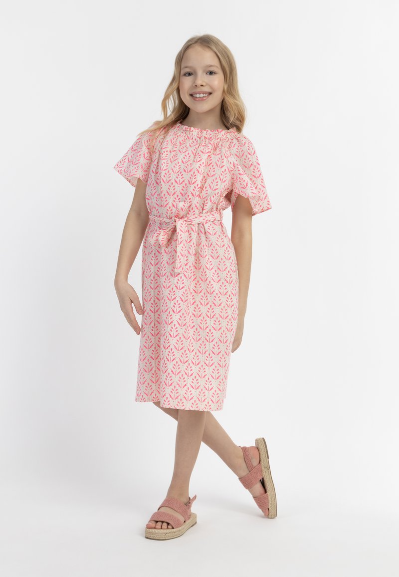 Vestido rosa con estampado, mangas cortas y con volantes, cintura atada y corte a la altura de la rodilla. Combinado con sandalias ligeras de tiras en rosa.