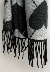 Black and gray patterned scarf featuring large heart shapes, woven texture, and long, black fringes along the edge.