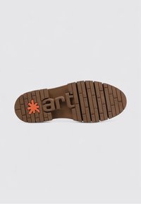 Suela marrón de zapato con un patrón de surcos y texto en relieve "art" con un asterisco naranja cerca del talón, sobre un fondo blanco.