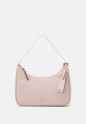 Sac à épaule rose clair DKNY avec une seule bandoulière, une fermeture éclair dorée, et une étiquette assortie attachée sur un fond uni.