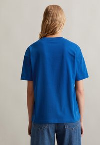 Blaues Baumwoll-T-Shirt mit kurzen Ärmeln, Rundhalsausschnitt und lockerer Passform. Die Rückseite hat eine glatte Textur ohne sichtbare Grafiken.