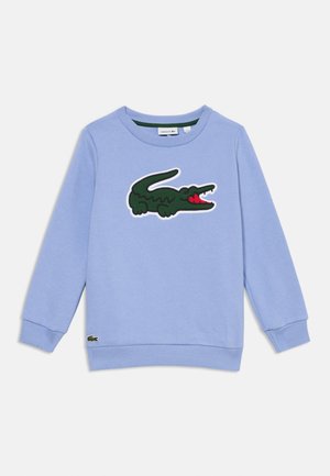 Sweat-shirt bleu clair en coton avec un col et des poignets côtelés. Présente un logo de crocodile vert avec des accents rouges à l'avant.