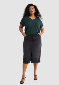 Teal textured top s výstřihem do V a s ohrnutými rukávy, doplněný černou denimovou midi sukni s předním rozparkem a dvěma bočními kapsami. Černé sandály.