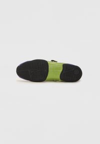 Calçado verde com sola de borracha preta, apresentando um acabamento texturizado e detalhes em roxo. Inclui fechos e detalhes metálicos na lateral.