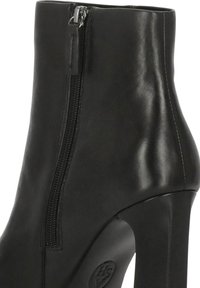 Stivaletto alla caviglia in pelle nera con cerniera laterale, tacco alto e texture liscia. Presenta una punta arrotondata e dettagli di cucitura delicata.