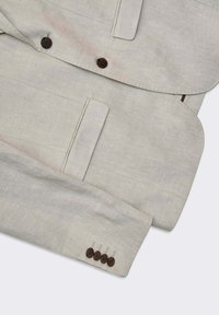 Ljusgrå linnakavaj med två framfickor och bruna knappar på ärmarna. Slät textur med strukturerade slag.