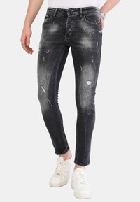 Slim-fit zwarte spijkerbroek van denim met doorleefde accenten, vervaagde textuur en gele spetters. Heeft klassieke zakken en riemlussen.