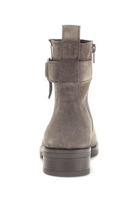 Bottine en suède gris avec une finition texturée, un talon carré, une fermeture éclair arrière et un détail de sangle sur le côté pour une touche de design supplémentaire.