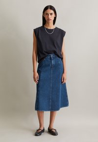 Dark grey sleeveless top, high-waisted blue denim midi skirt, and black ballet flats. Smooth texture with minimalist design and stitching details.