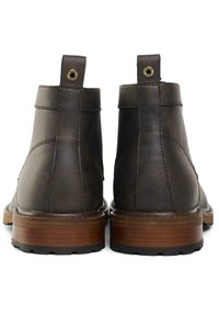 Brown leather boots with a low heel, rounded toe, and ankle height. Features a stitched design and a rear pull tab for easy wear.