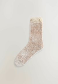 Soft beige sock with a textured pattern, featuring a fluffy white cuff. The material appears warm and cozy. Shape is standard for ankle-length wear.