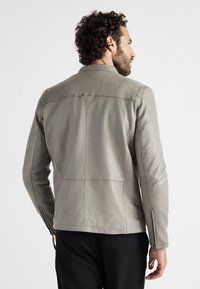 Grå læderjakke med en tætsiddende pasform, lynlåslommer og synlige syninger. Glat tekstur med et minimalistisk design.