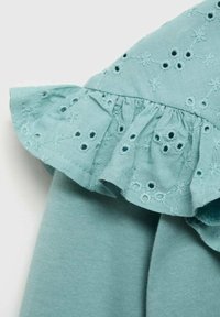 Světlý tyrkysový bavlněný top s volánkovým límcem a výšivkou květinových vzorů a perforacemi. Měkká textura, ležérní design.
