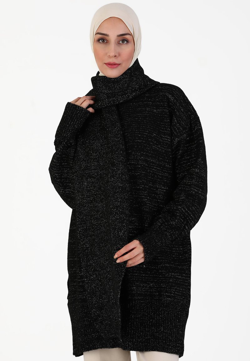Black knitted oversized sweater, featuring a high neck, long sleeves, and a textured pattern with subtle metallic threads for accent.