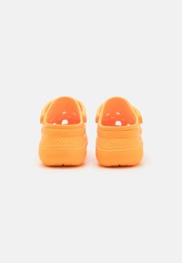 Orange Crocs klipklapper med et glat, let design, bagstropper, ventilationshuller og prægede logoer på hælen.