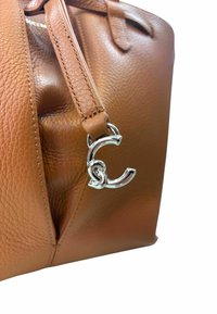 Borsa a tracolla in pelle marrone con finitura texturizzata, caratterizzata da un accento in catena argento e un charm con il logo CC sulla tracolla.