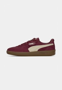 Burgundowe zamszowe sneakersy z beżowym paskiem PUMA, płaską brązową gumową podeszwą i wiązanym zapięciem. Logo PUMA Palermo na języku.