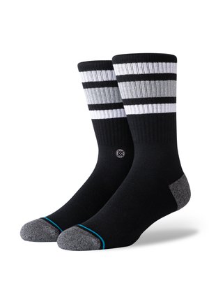 Black socks with white and gray horizontal stripes at the top. Reinforced gray heel and toe, featuring a small logo near the ankle. Smooth texture.