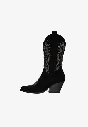 Bota de cowboy de ante negra con punta afilada, tacón elevado y diseño de llamas bordado en plata a los lados. Textura suave, forma estructurada.