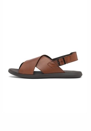 Brown leather sandals with an open toe, cross-strap design, and adjustable ankle strap. Textured accents and a flexible black sole.