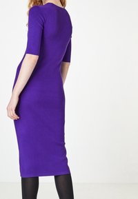 Robe violette ajustée à manches courtes, longueur genoux, fabriquée en tissu lisse. Présente un décolleté rond et un design simple et uni.