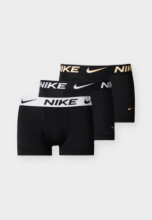 Tri para crnih Nike bokserica s različitim brendiranim pojasom u bijeloj, crnoj i zlatnoj boji, složene jedna na drugu na jednobojnoj pozadini.