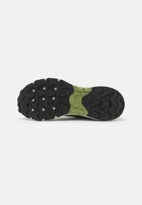 Suela de zapato con patrón de banda de rodadura multidireccional en negro y sección media verde, diseñada para ofrecer tracción y estabilidad al aire libre.