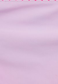 Svetlo roza tkanina z gladko teksturo, ki ima obrobo iz majhnih roza krogov ob zgornjem robu.