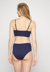 Top de biquíni canelado azul-marinho com alças ajustáveis e parte de baixo de cintura alta. Design simples com uma textura suave e sem padrões visíveis.